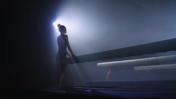 젊은 여성 운동 선수가 밤에 혼자 훈련하고 느린 모션 샷 균형 광선에 운동을 하고 있습니다 — 비디오