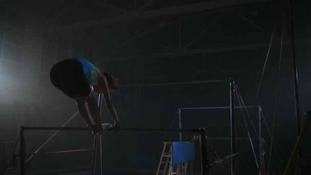 Träning av junior kvinnlig gymnast, utföra tricks på ojämna barer, träningsövningar på sportig utrustning — Stockvideo