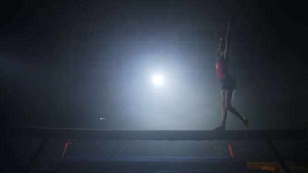 Jonge vrouwelijke turnster danst op balansbalk, artistieke gymnastiek training of wedstrijd, slow motion shot — Stockvideo