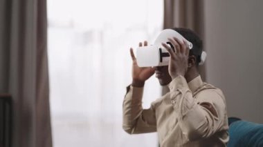 Afro-Amerikalı adam evde oturarak eğitim ve eğlence için video gözlüğü kullanıyor.