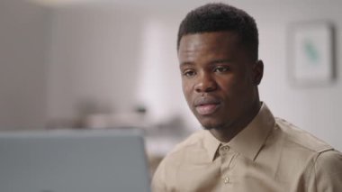 Genç Afro-Amerikalı adam internet üzerinden iletişim kuruyor, laptop kullanıyor, web kamerasına bakıyor ve konuşuyor.