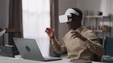 Siyah adam işine konsantre olmaya çalışıyor, masada dizüstü bilgisayarla oturuyor ve zor düşünüyor, serbest çalışan biri evde çalışıyor.