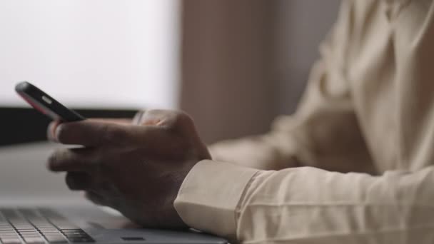 Irodai dolgozó használ okostelefon munkahelyi, ellenőrzése szociális hálók munka közben, közelkép a kezét fekete ember — Stock videók