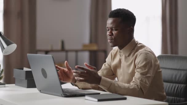 Fiatal fekete üzletember kommunikál videohívással laptopon kollégákkal vagy alkalmazottakkal, online üzleti találkozó, távolról dolgozik — Stock videók