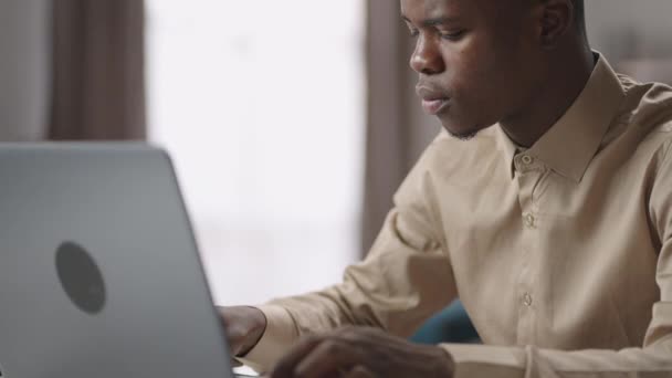 Studente maschio nero sta lavorando con il computer portatile, l'invio di messaggi nelle reti sociali o in chat di lavoro, ritratto girato — Video Stock