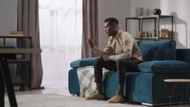 Kaygısız genç Afro-Amerikan adam arkadaşlarıyla video aracılığıyla iletişim kuruyor. Akıllı telefondan, odadaki boy portresiyle.