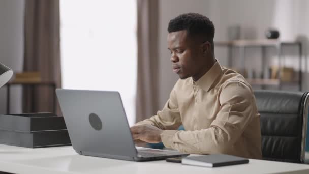 Fiatal fekete férfi tanul online, megtekinti a tanulási videót a laptopon, és jegyzetel pad, önképzés — Stock videók