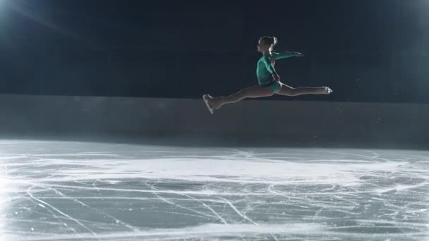 Giovane pattinatrice single femminile sta eseguendo elementi sulla pista di pattinaggio sul ghiaccio la sera, sportiva sta pattinando e saltando — Video Stock