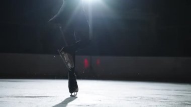 Artistik patinajcı kadın siyah spor giyer buz pistinde paten kayar, geceleri tek başına antrenman yapar ve yarışmaya hazırlanır.