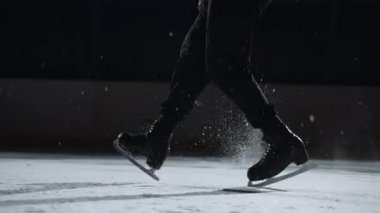 Sporcu buzda dans ediyor, buz pistinde adımlar atıyor, ayakların yakın çekimi, ayak parmakları ve patenlerin üzerinde duruyor.