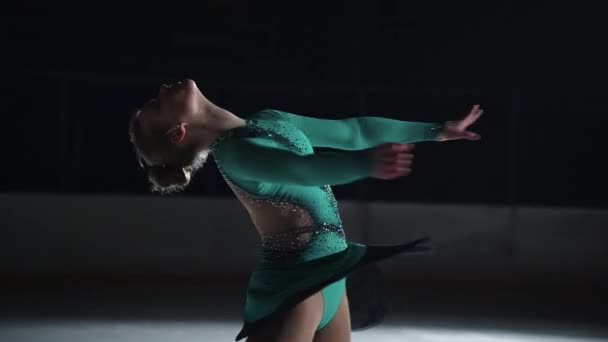 Спортивна дівчина робить обертання фігурного катання на ковзанах в темряві, тренування в юнацькому спорті, повільний рух постріл — стокове відео