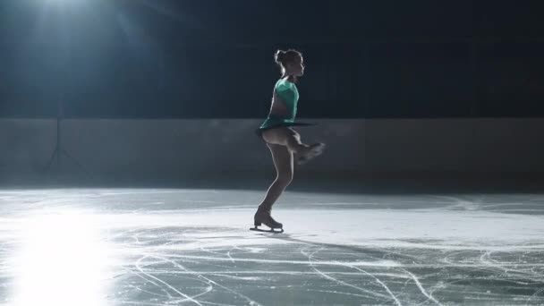 Junior female figure skater is performing alone on ice rink, young sports girl is doing spin, slow motion shot — Stock video