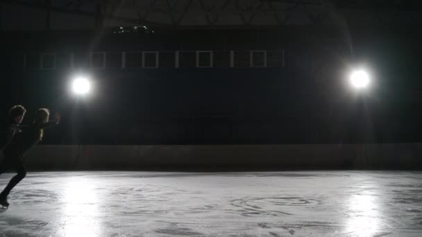 Par de jovens patinadores artísticos está patinando no ringue de gelo, de mãos dadas, programa de treinamento para o campeonato, câmera lenta — Vídeo de Stock