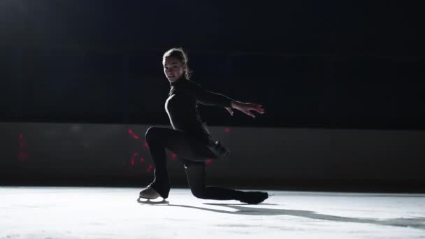 Hermosa joven deportista está patinando en pista de hielo en la oscuridad, la realización de elementos de patinaje artístico — Vídeo de stock