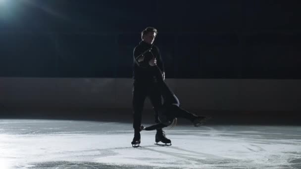 Joven profesional deportivo hombre y mujer están entrenando, patinaje artístico spin, par de patinadores de la figura están ensayando nuevo programa en pista de hielo — Vídeos de Stock
