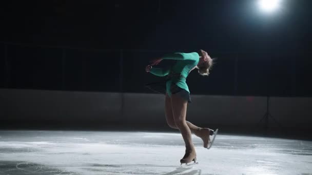 Beautiful spin elements in figure skating, sporty girl is performing on ice rink in darkness, training and demonstration performance in single skating sport — Stock Video