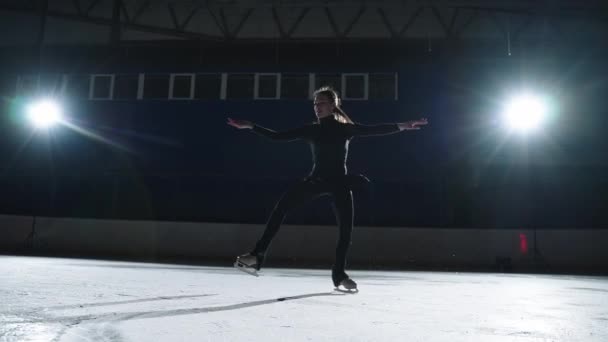 Giovane donna atletica sta eseguendo elementi di pattinaggio artistico su pista di pattinaggio, allenamento di sportiva professionista — Video Stock