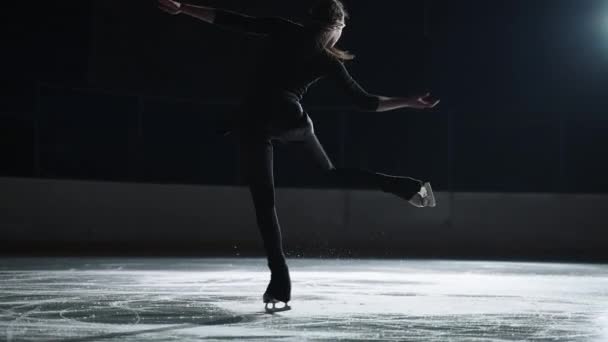 Młoda kobieta łyżwiarka figurowa trenuje Biellmann spin na lodowisku, sportowiec dziewczyna jest sukienki czarny strój sportowy, ćwiczenia nowych elementów — Wideo stockowe