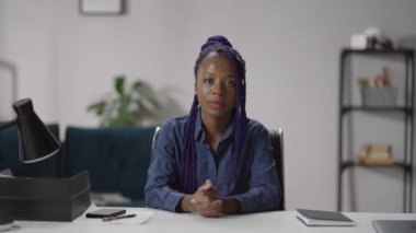 Mutlu, Afro-Amerikalı bir kadın evinde oturmuş kameraya bakıyor, arkadaşça gülümsüyor ve internette sohbet ediyor.
