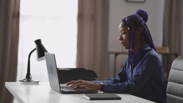 Серьезная афро-американская деловая женщина работает с ноутбуком в офисе, молодая черная леди печатает и отправляет сообщения — стоковое видео