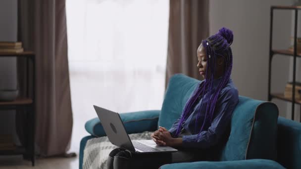 Mulher afro-americana está chamando por videoconferência no laptop para especialista ou amigo, comunicação on-line pela internet, sentado sozinho em casa — Vídeo de Stock