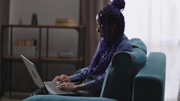Estudiante afroamericana está aprendiendo en línea en casa, la señora está utilizando el ordenador portátil, escribiendo texto en el teclado — Vídeo de stock