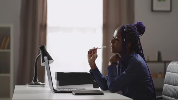 Estudiante afroamericana se prepara para el examen, aprender en casa con laptop, sentarse a la mesa y pensar o reflexionar — Vídeo de stock