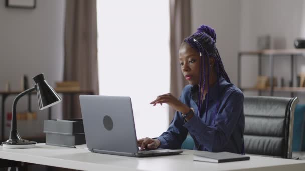 Bella donna di colore sta lavorando in remoto da casa, seduto a tavola e l'invio di messaggi dal computer portatile, seo-manager — Video Stock