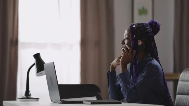 Freelancer αφρο-αμερικανική γυναίκα μιλάει από το κινητό τηλέφωνο κατά τη διάρκεια της εργάσιμης ημέρας στο γραφείο στο σπίτι, κουβεντιάζοντας με το κινητό τηλέφωνο — Αρχείο Βίντεο