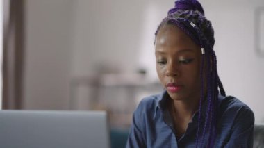 Mor saçlı siyahi kadın portresi odada dizüstü bilgisayarla çalışıyor, sergileniyor, Afro-Amerikalı genç bayan