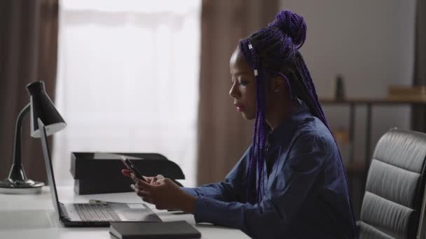 Mulher de negócios preta está usando smartphone no local de trabalho no escritório, digitando e enviando mensagens, jogando jogos — Vídeo de Stock