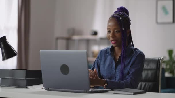 Mulher negra alegre está se comunicando por videochamada on-line no laptop, olhando em exposição e sorrindo, reunião de negócios remota — Vídeo de Stock