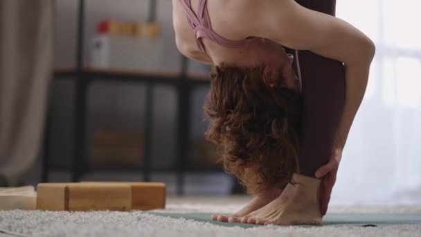 Стройная спортивная женщина делает растяжку тренировки, выполняя утренние тренировки в гостиной, взрослая женщина делает упражнения — стоковое видео
