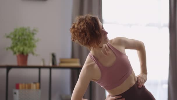 Kvinna tränar ensam i vardagsrummet, medium porträtt av smal sportig dam, hälsosam livsstil, gå ner i vikt — Stockvideo