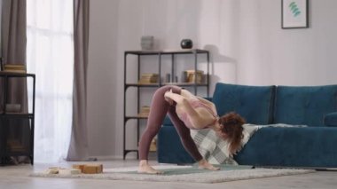 İnce kadın, dairesinin, spor ve aktif yaşam tarzının, fiziksel egzersizlerinin oturma odasında tek başına antrenman yapıyor.