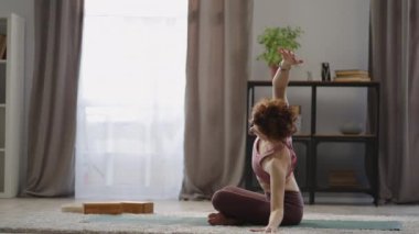 Yetişkin kızıl kadın evde omurga egzersizleri yapıyor. Yoga yapıyor, oturma odasında antrenman yapıyor.