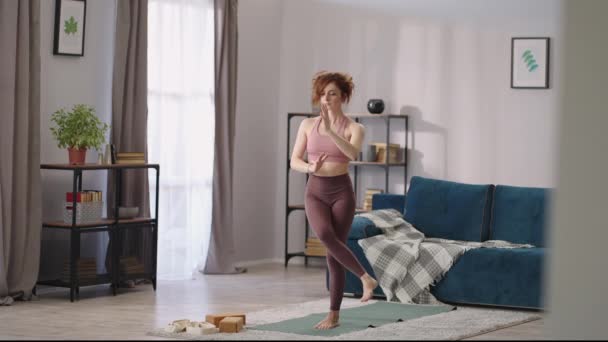 Frau praktiziert Yoga, Übungen für eine gute körperliche Kondition, Ausführung von Übungen für das Gleichgewicht, Dame steht auf einem Bein — Stockvideo