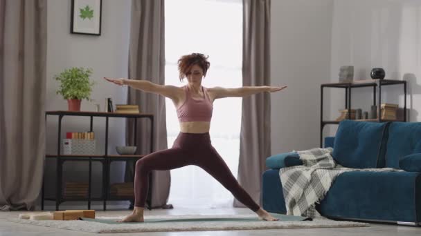 在家里进行瑜伽训练，成年女子在房间里摆姿势，双腿站立，进行体育活动以保持健康 — 图库视频影像