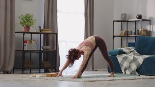 Entrenamiento de yoga de una joven esbelta en casa, la señora está de pie en la sala de estar y el entrenamiento, haciendo asanas estáticas — Vídeos de Stock