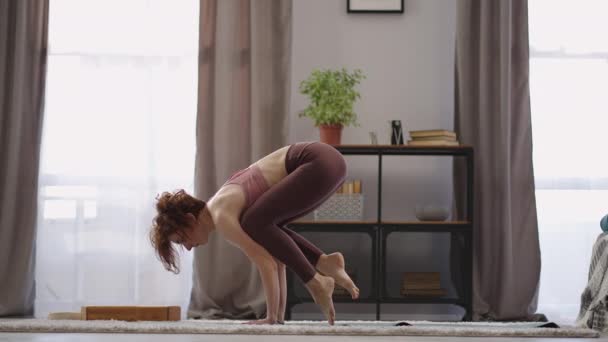 Idrottskvinna utför asana hemma på morgonen, lyfta sin kropp från golvet med händerna, utföra fysiska övningar — Stockvideo