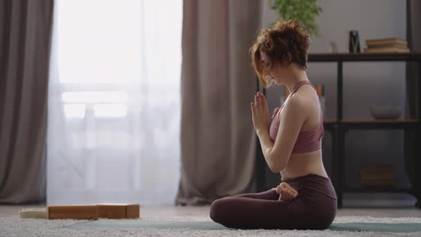 Meditação de ioga em casa, mulher adulta está sentada no chão no quarto, fazendo posição de lótus, mãos dobráveis e contemplando — Vídeo de Stock