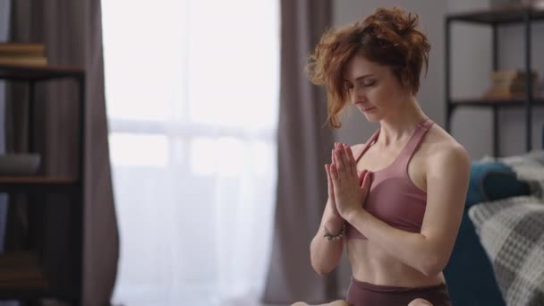 Evde yoga meditasyonu, spor kadın nilüfer pozisyonunda yerde oturuyor, ellerini göğsüne koyuyor, sakin meditasyon atmosferi — Stok video