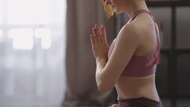 Mulher yogi relaxado está meditando em casa, sentado em posição de lótus na sala de estar, olhos fechados, prática de ioga e meditação — Vídeo de Stock