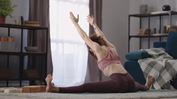 Sportliche Frau macht Spaghetti- und Dehnübungen, trainiert allein zu Hause, Yoga und Gymnastik — Stockvideo