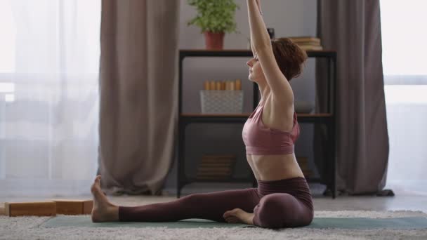 Entrenamiento de hatha yoga en casa, la mujer está sentada en el suelo en la sala de estar, la señora está realizando ejercicios para la salud corporal — Vídeo de stock