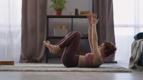 Paripurna navasana Boot Pose, Frau führt Workout in Wohnung, sitzt auf dem Boden und hält Beine in der Luft — Stockvideo