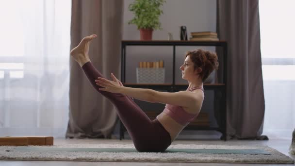 Sportliche Frau führt Yoga-Asanas für Gleichgewicht und Kraft durch, Paripurna navasana Boot Pose, weibliche Figur — Stockvideo