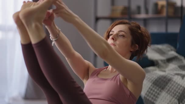 Hausfrau führt Paripurna Navasana Boot Pose, während der Yoga-Workout zu Hause, die Balance des Körpers zu halten — Stockvideo