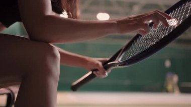 Genç esmer bayan spor giyinmiş spor giyim, tenis kortunda yedek kulübesinde oturuyor.