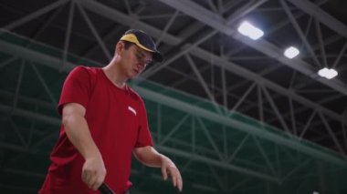 Genç adam tenis kortunda antrenman yapıyor, yere top atıyor ve yakalayıp, içeride portre çekimi yapıyor.